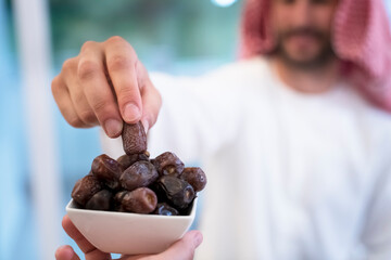 modern multiethnic muslim family sharing a bowl of dates while enjoying iftar dinner together during a ramadan feast at home