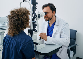 Checking eyes of child in ophthalmology clinic. Curly boy getting eye exam at ophthalmology clinic...