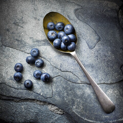 Blue berries and single spoon top view on a slate background fine art.