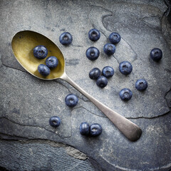 Blue berries and spoon top view on a slate background fine art.