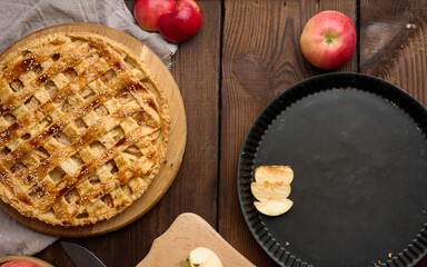Round baked apple pie on a brown wooden table, top view