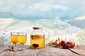Kettle of delicious and healthy tea with lemons, oranges and fruits on snowy mountain background
