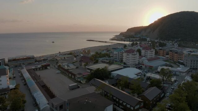 Flight over the coastline at sunset. Drone video footage. Houses, roads, green hills. Human and nature. Top view