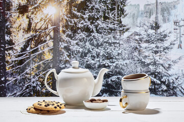 Obraz na płótnie Canvas Kettle and two cups of delicious tea with chocolate cookies on winter forest background