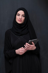 Young modern muslim business woman using smartphone wearing hijab clothes in front of black chalkboard