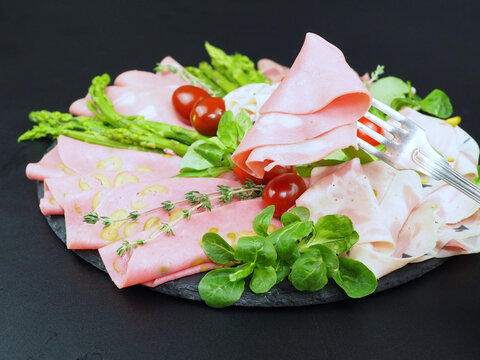 Sliced ham, sausage with olives, vegetables and herbs