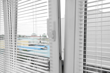 Stylish window with horizontal blinds in room