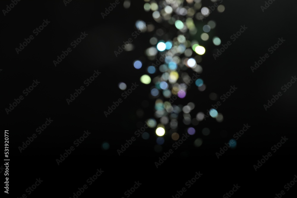 Wall mural blurred view of colorful festive lights on black background. bokeh effect