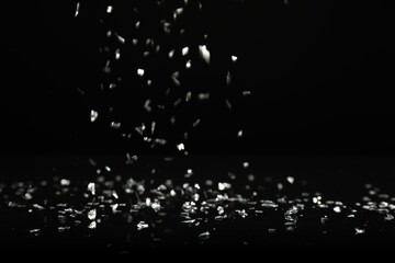Shiny silver glitter falling down on black background. Bokeh effect
