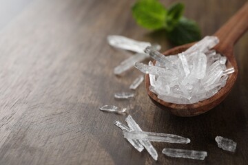 Menthol crystals on wooden background, closeup. Space for text