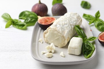 Delicious goat cheese with basil and figs on white wooden table