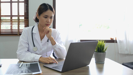 Portrait happy asian woman doctor, Telemedicine concept. Asian female doctor talking with patient using laptop online video webinar consultation while sitting in clinic office - Powered by Adobe