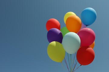 Bunch of colorful balloons against blue sky. Space for text