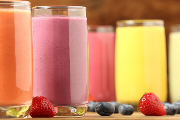 Glasses with different tasty smoothies on wooden table, closeup