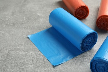 Rolls of different color garbage bags on light grey stone table