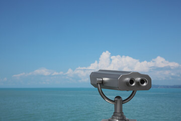 Metal tower viewer installed near sea, space for text. Mounted binoculars