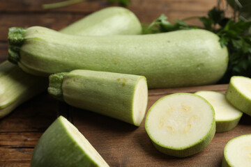 Cut and whole ripe zucchinis on wooden table, closeup