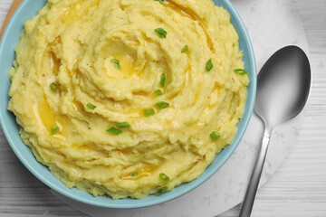 Bowl of tasty mashed potatoes with onion served on white wooden table, above view
