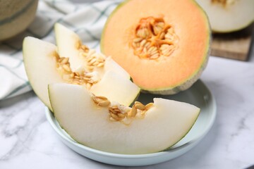 Tasty colorful ripe melons on white marble table, closeup