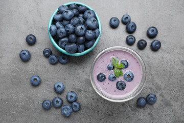 Glass of blueberry smoothie with mint and fresh berries on grey table, flat lay