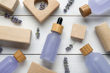 Fototapeta na wymiar Flat lay composition with bottles of essential oil and flowers on white wooden table