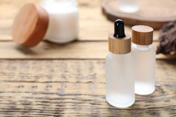 Bottles of essential oil on wooden table, closeup. Space for text