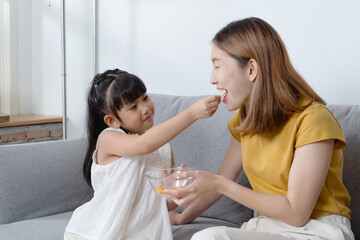 Obraz na płótnie Canvas Portrait of daughter feeding snack to her mother.