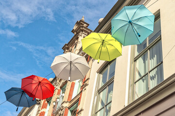 Fototapeta na wymiar Colorful umbrellas in the air against blue sky with clouds