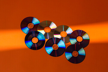 Large Variety of Arranged CD Disks or DVD Disks on Orange Background With Different Linear Patterns...