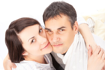 Closeup Portrait of Caucasian Family with Pregnant Whife and Handsome Husband While Posing Together and Embracing His Woman Over White