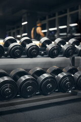 Naklejka na ściany i meble Rows of dumbbells in the gym. Modern sports gym. Rows of dumbbells and a bodybuilder blurred on the background.