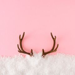 Creative flat lay holiday background made with reindeer antlers and snow on pastel pink background. Minimal Christmas deer concept. New year greeting card with copy space. © Goncharuk film