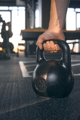 Naklejka na ściany i meble Close-up of a muscular hand holding a kettlebell. Athlete hand gripping a kettlebell in gym