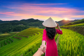 Asian woman wearing Vietnam culture traditional holding man's hand and leading him to rice terraces in Mu Cang Chai, Yen Bai, Vietnam.
