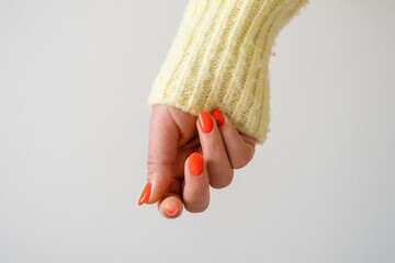 Closeup of hands of a young woman with orange manicure on nails