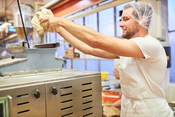 Baker apprentice holds fresh dough in his hands
