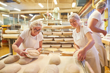 Baker team with boss and apprentices baking bread - obrazy, fototapety, plakaty