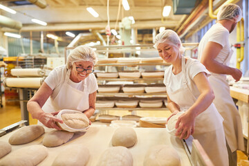 Baker team with boss and apprentices baking bread