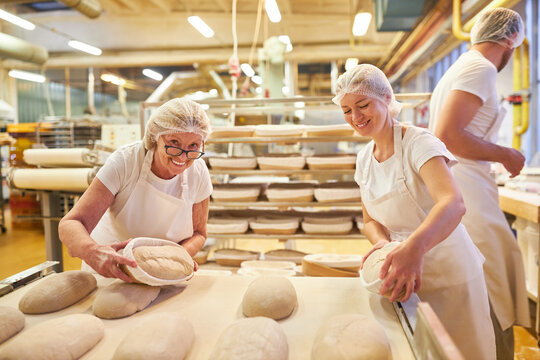 Baker team with boss and apprentices baking bread