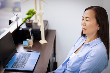 Serene businesswoman with eyes closed at laptop