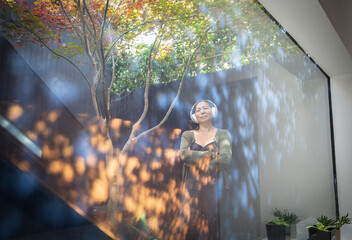 Serene woman with headphones on courtyard with reflections