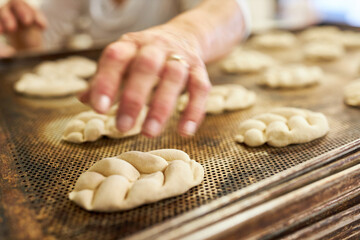 Hand of a baker baking yeast plaited bread on a tray