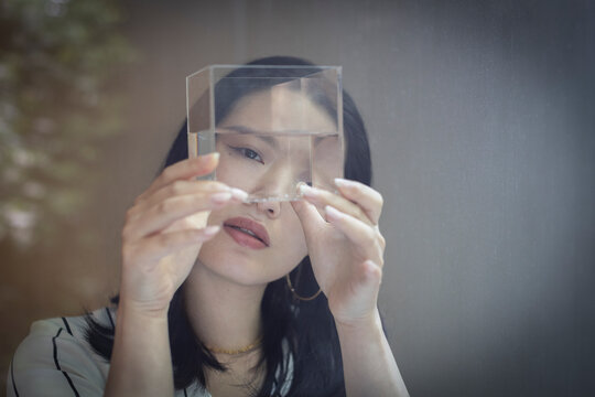 Curious female designer looking at cube with water