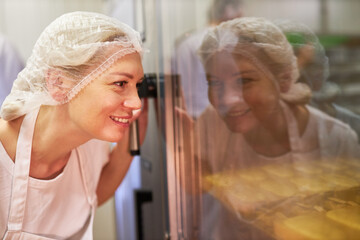 Baker apprentice controls baked goods in the oven