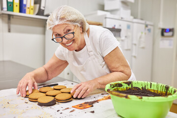 Experienced baker decorates double biscuits with chocolate
