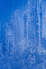 Fototapeta na wymiar Frosty patterns on the glass, the dawn sun through the frost, blue abstract winter background