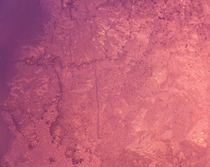 Frosty patterns on the glass, the dawn sun through the frost, purple abstract winter background