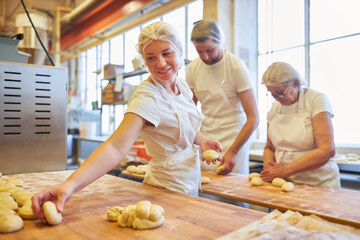Bakers bake together small buns in bakery