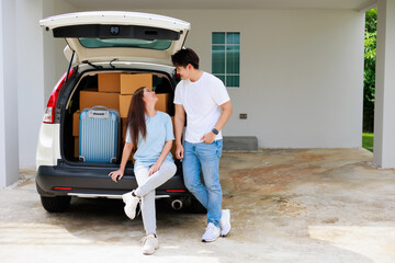 Nice asian couple feel happy that moving to new house and they happy, smile and  talking while sitting in the back of car that have many cardboard boxes and luggage . Moving day.