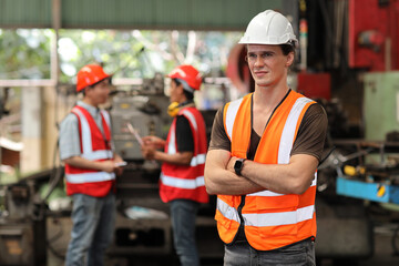 Technician engineer in protective uniform standing and using walkie talkie radio while controlling operation or checking industry machine process with hardhat at heavy industry manufacturing factory